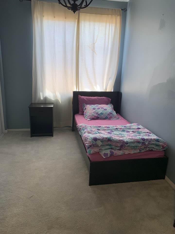 A simple bedroom with a single bed and nightstand by the window.