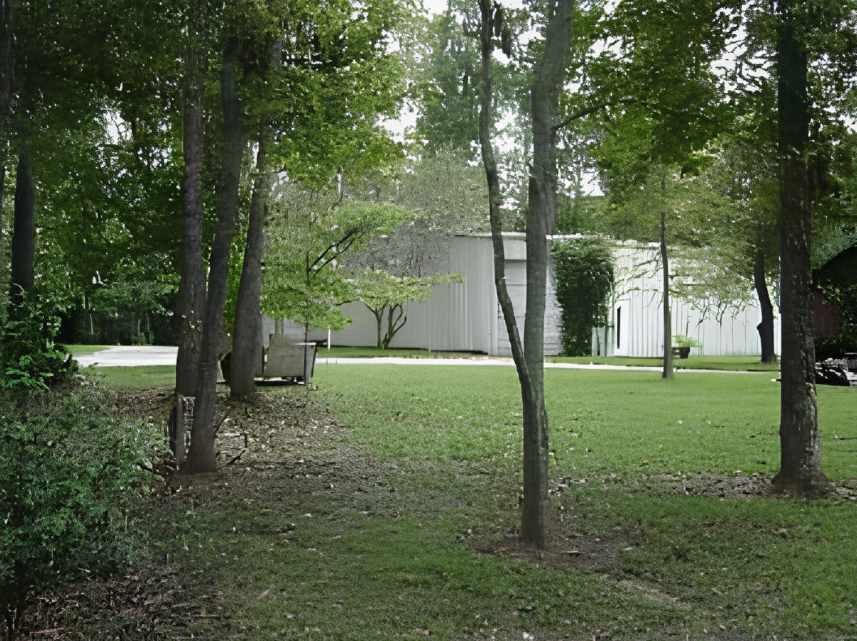 A modern house surrounded by trees and a grassy yard.