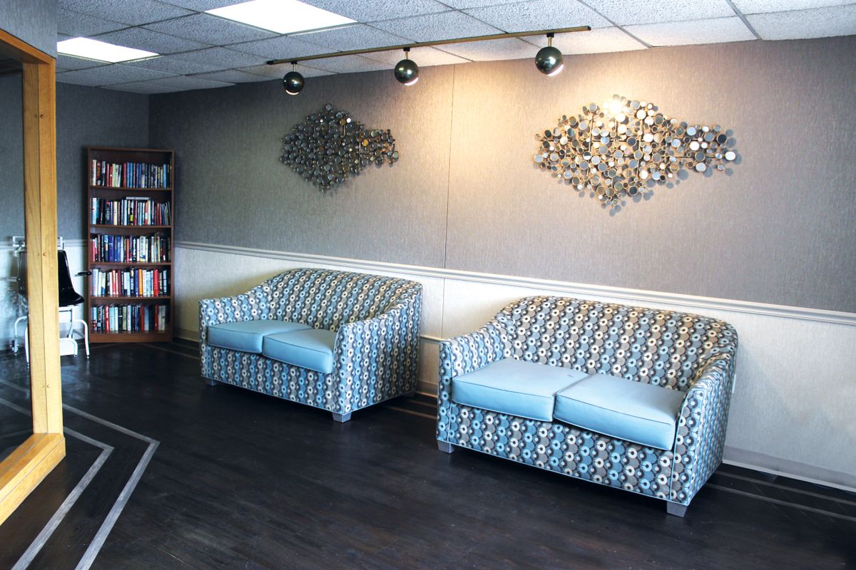 A modern waiting room with patterned sofas and decorative wall art.