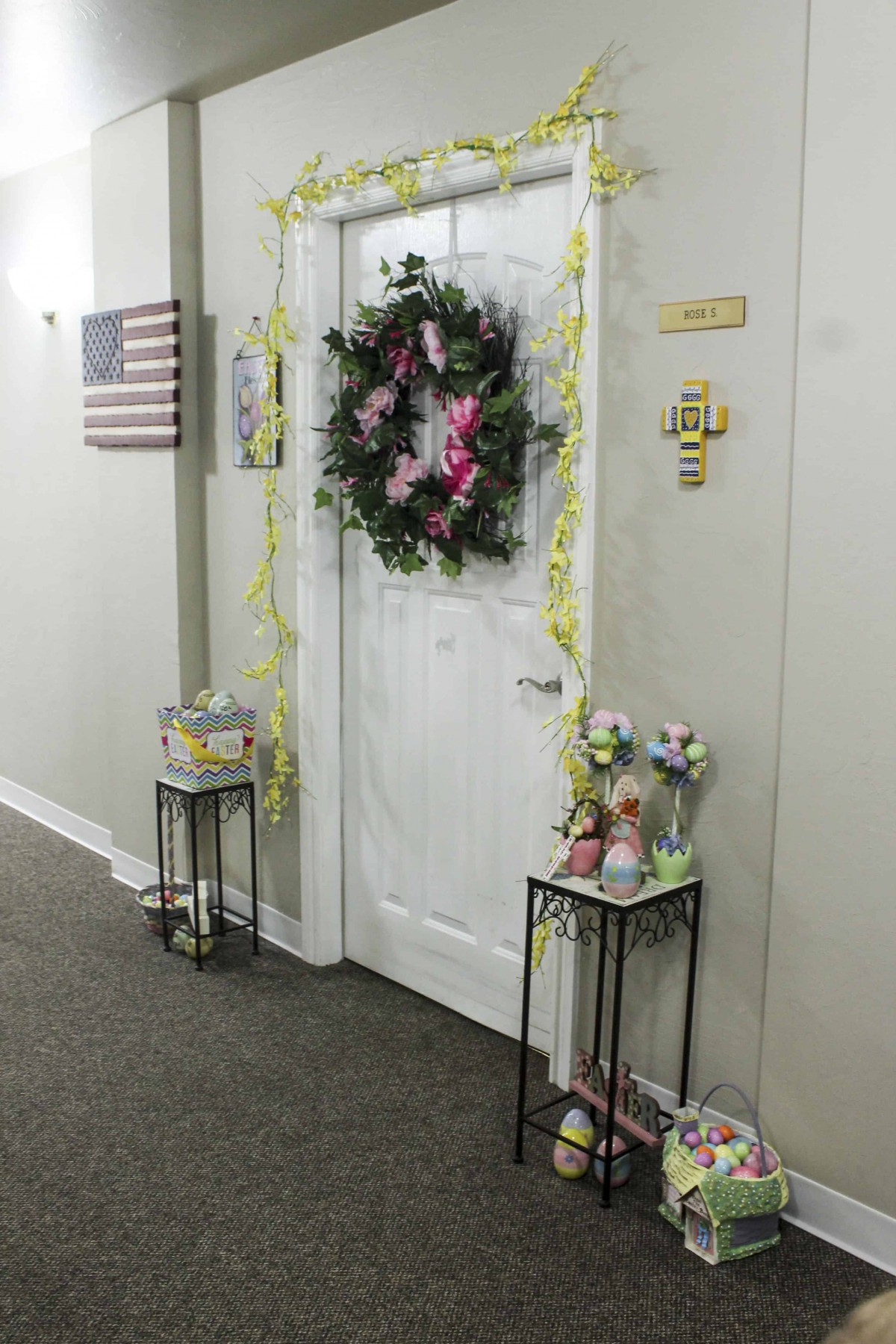 A decorated doorway with a wreath and flowers in a hallway.