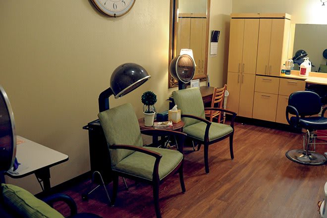 A vintage salon interior featuring retro chairs, hairdryers, and a large mirror.