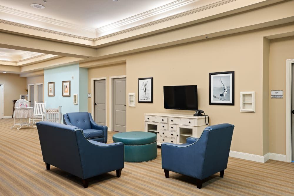 A modern living room with blue armchairs, a television, and framed artwork on the walls.
