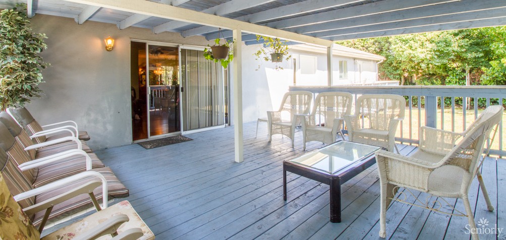 A cozy outdoor patio with seating and hanging plants.