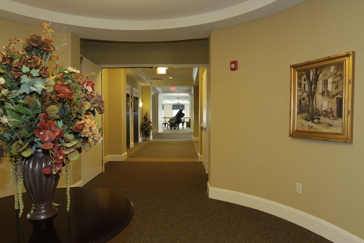A well-decorated hallway with a distant view of a piano.