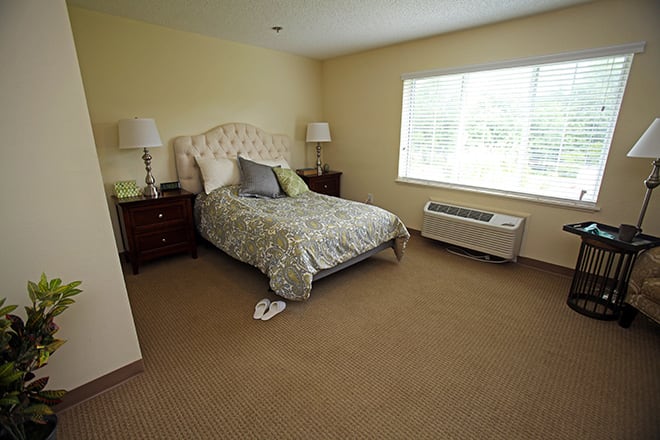 A cozy and well-lit bedroom with a neatly made bed and matching nightstands.