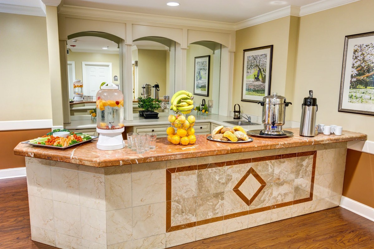 A hotel breakfast buffet with a variety of fruits, fresh orange juice, and coffee.