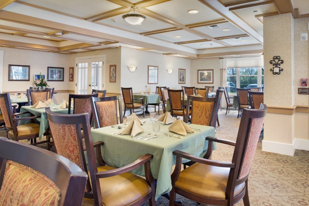 An elegantly set dining area with neatly arranged tables and chairs, featuring bright and inviting lighting.