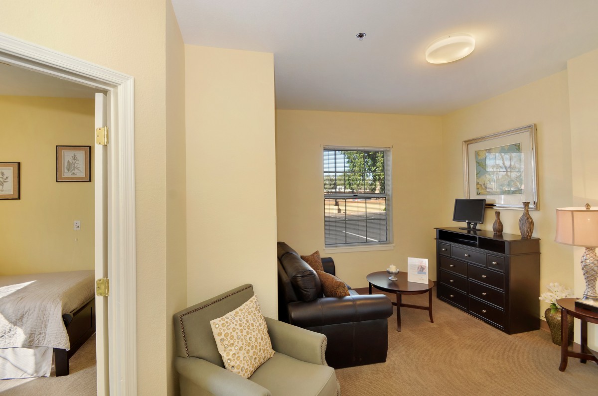A cozy living room with armchairs, a small table, and a window letting in natural light.