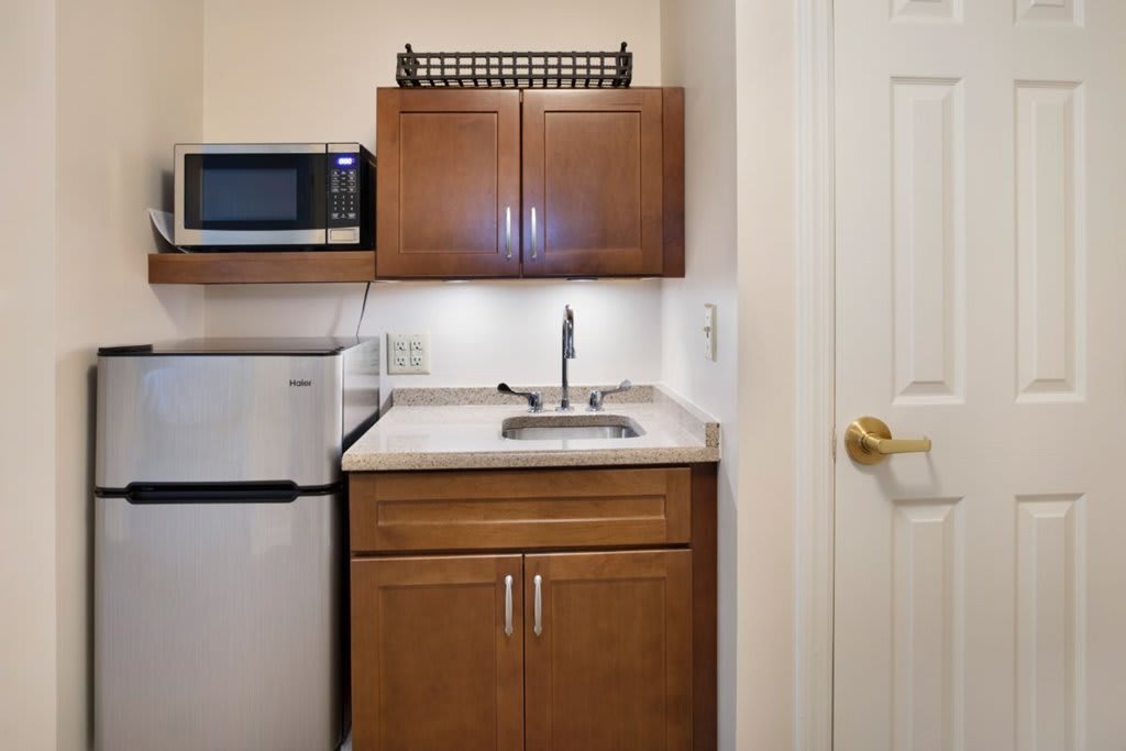Compact kitchenette with a microwave, refrigerator, and sink.