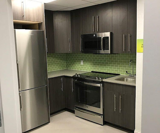 A modern kitchen featuring stainless steel appliances and a green tiled backsplash.