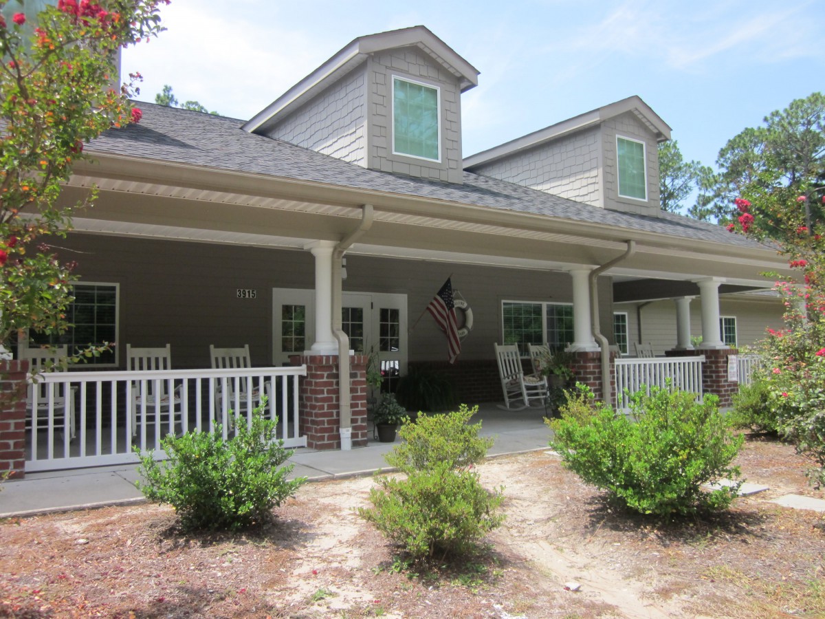 A charming house with a spacious porch and neatly landscaped front yard.
