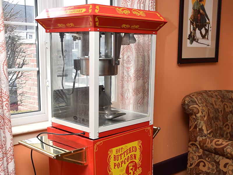 A vintage red popcorn machine placed indoors.