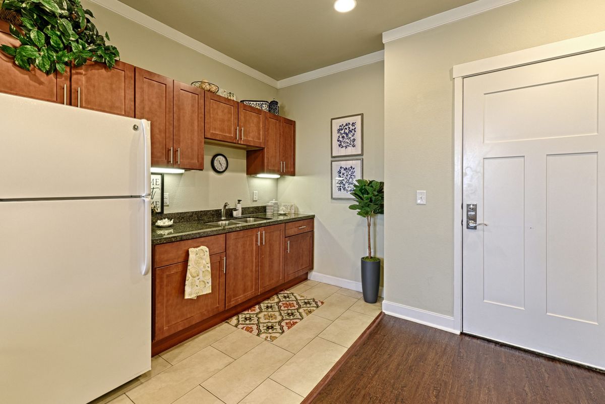 A modern apartment kitchen with wooden cabinets, a refrigerator, and decorative elements.