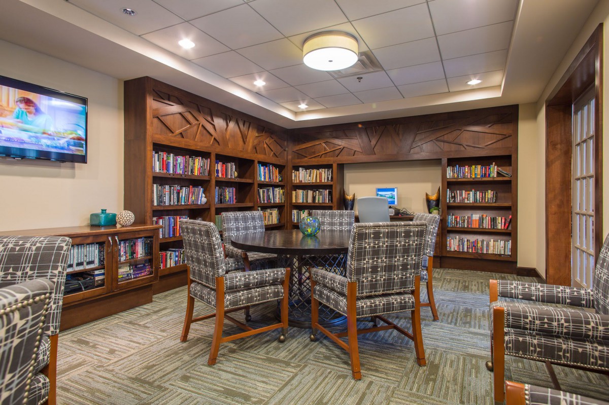 A cozy library reading area with bookshelves, a table, and chairs.