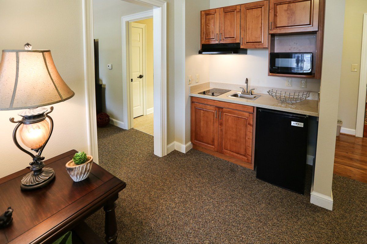 A cozy kitchenette in a small apartment with wooden cabinets and basic appliances.