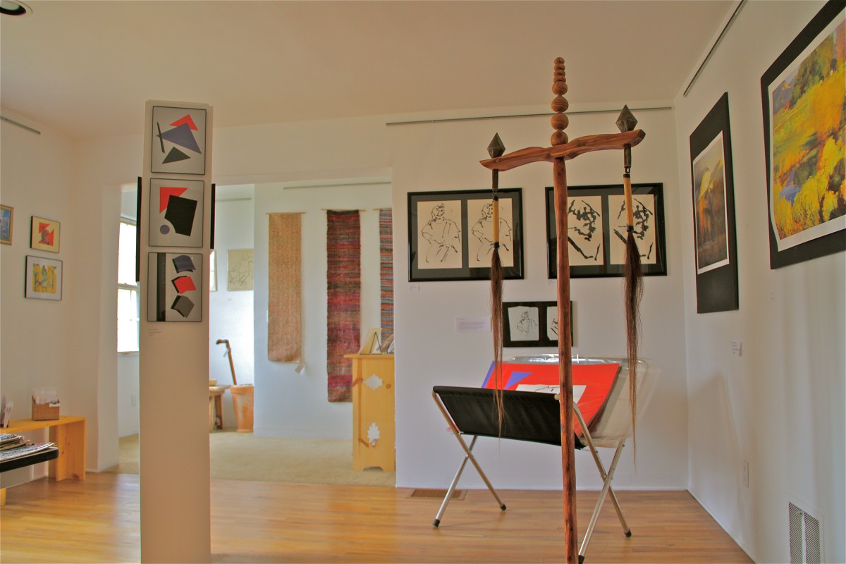 An art gallery showcasing various paintings and sculptures in a bright, open space.