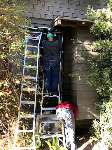 Workers using a ladder to perform maintenance on a house.