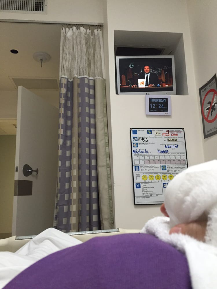 A patient resting in a hospital bed with a television mounted on the wall.