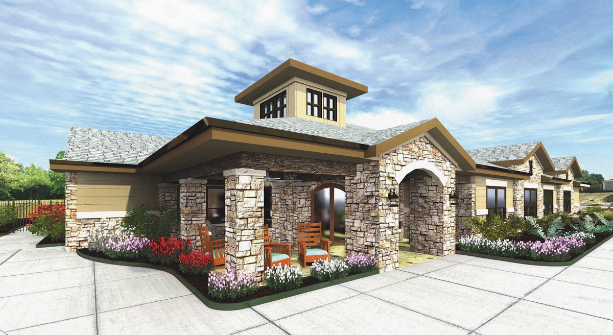 Stone entrance building with landscaping under a cloudy sky.