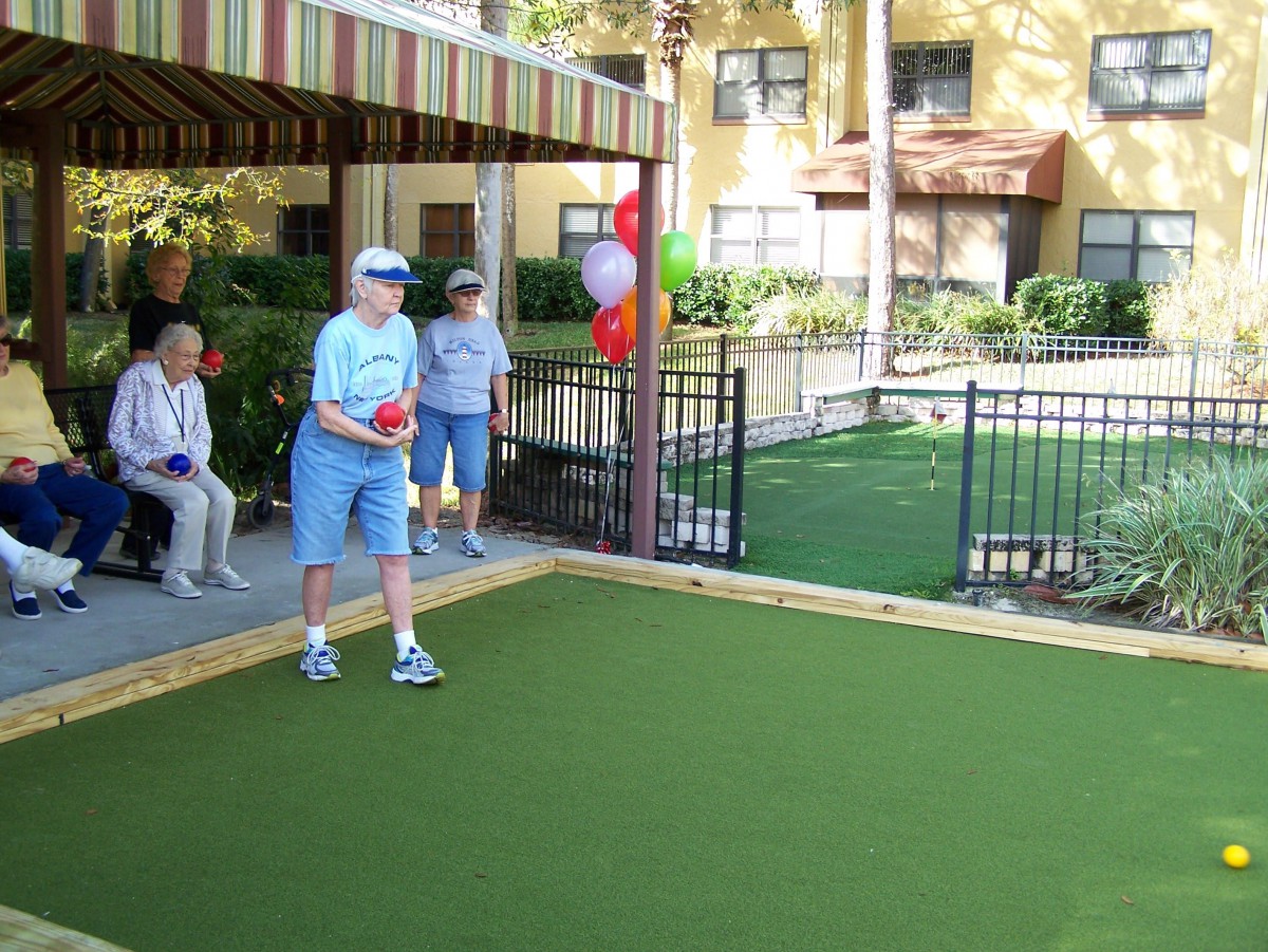 A group of elderly people enjoying a game of bocce in an outdoor setting.