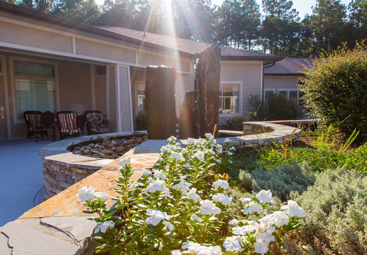 A sunlit garden with white flowers and a peaceful patio area.