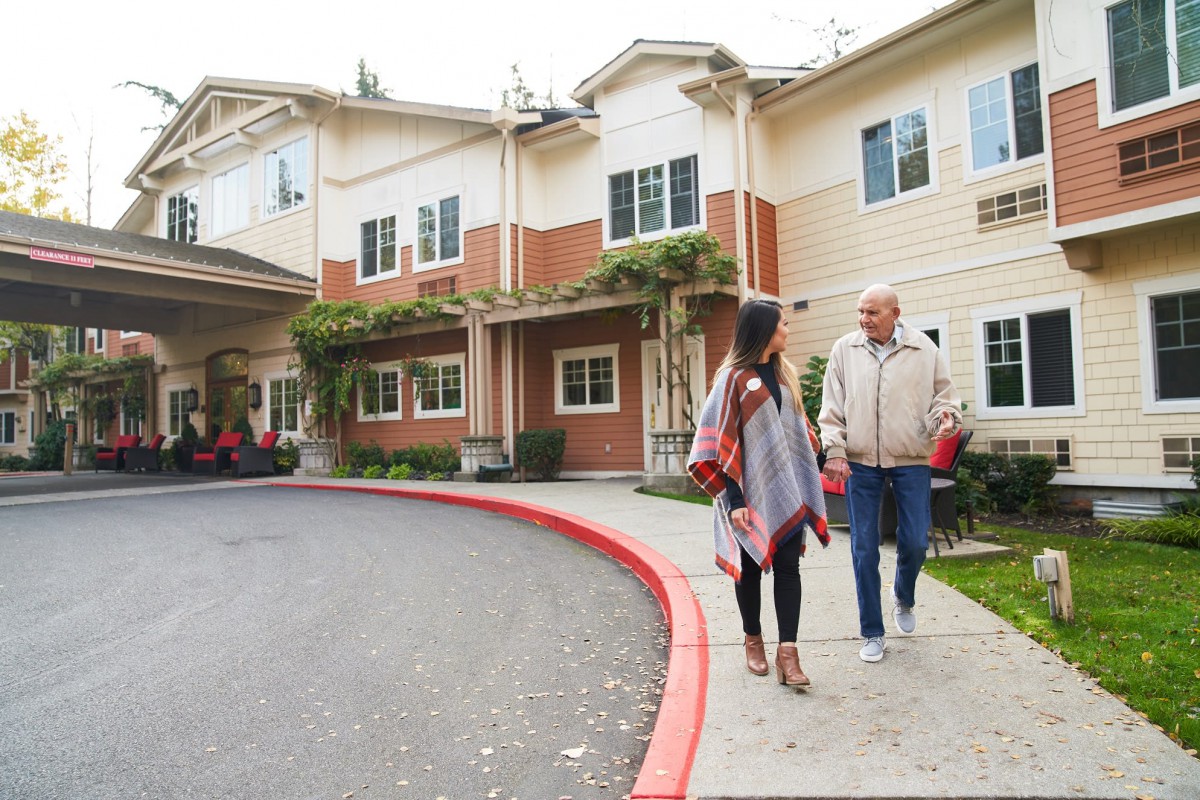 Two people walking and talking outside a residential building.