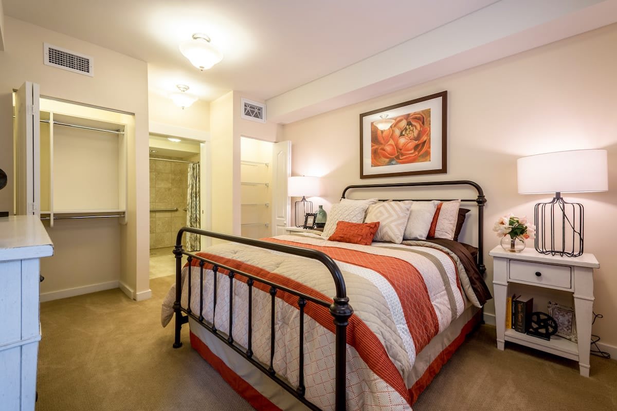 A cozy bedroom with a metal-framed bed, colorful bedding, and stylish decor.