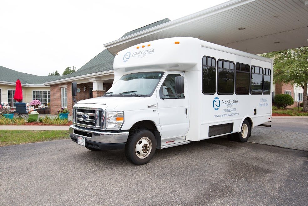 A white shuttle van parked in front of a building.