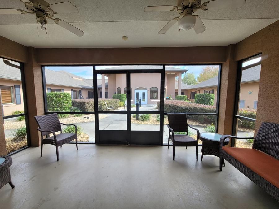 A sunroom with chairs and a table overlooking a courtyard.