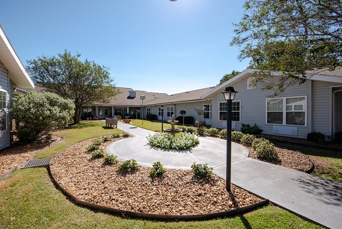 A well-maintained building with a landscaped garden and a winding pathway under a clear blue sky.