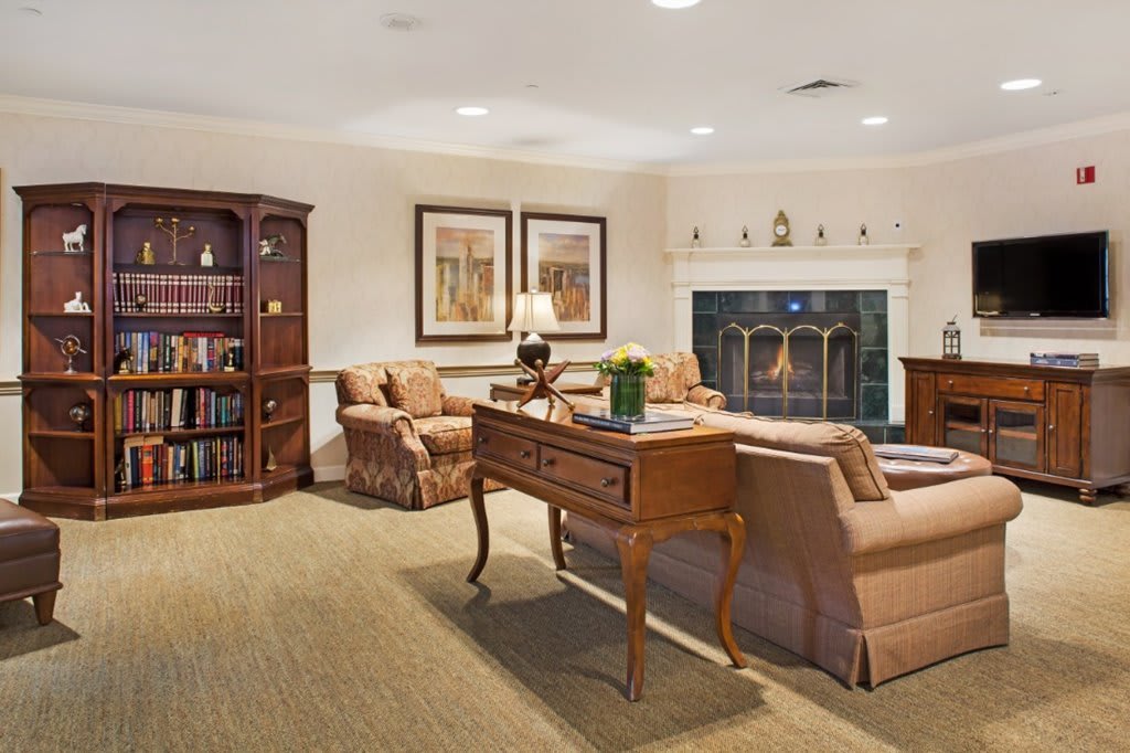 A cozy living room with a fireplace, sofas, and a wooden bookshelf.