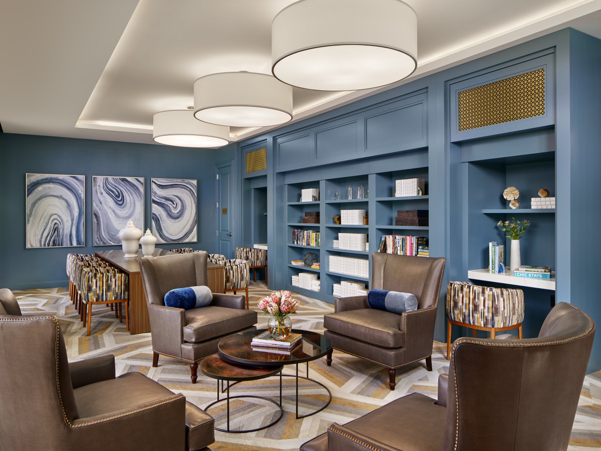 A modern lounge with blue walls, comfortable armchairs, and contemporary art pieces.