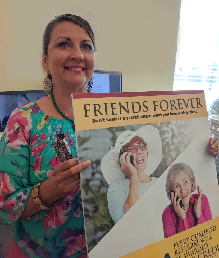 A woman holding a 'Friends Forever' poster with images of two elderly women.