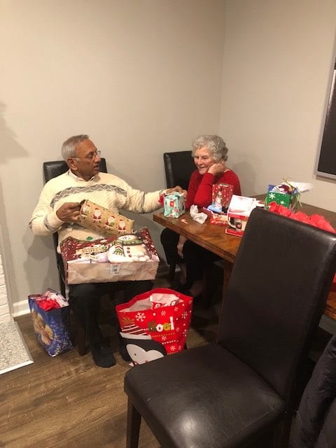 A cheerful moment as two people exchange gifts during a holiday celebration.