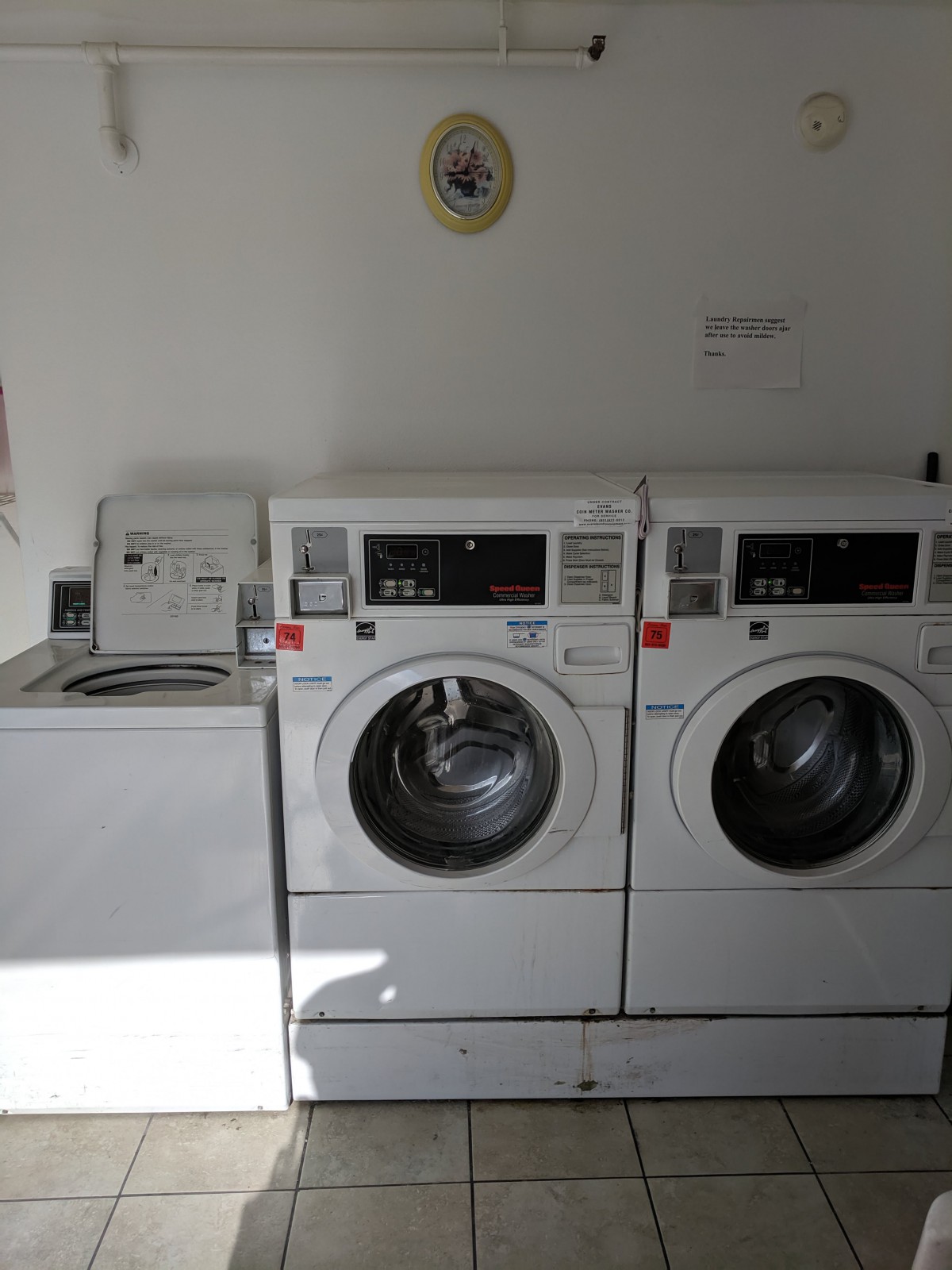 A laundry room featuring two front-loading washing machines and a dryer.