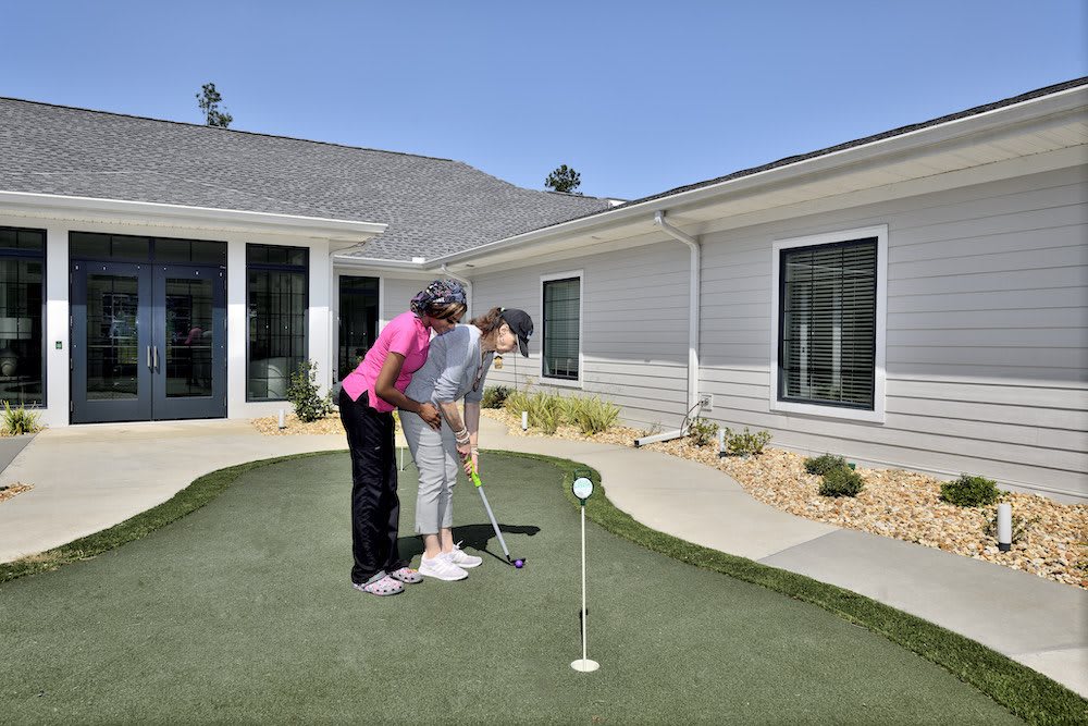 Two people practicing putting on an outdoor green.