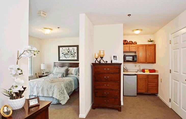 A cozy studio apartment featuring a compact kitchen and a well-decorated bedroom.