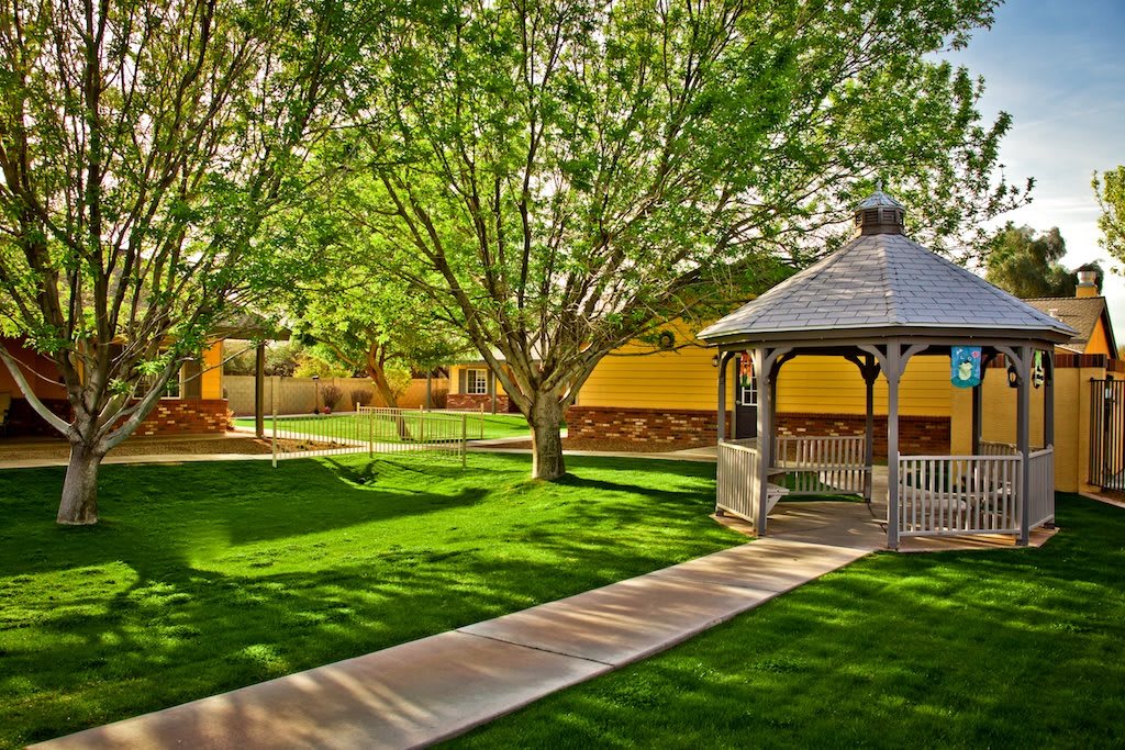 A scenic view of a park with a gazebo and pathway surrounded by lush greenery.