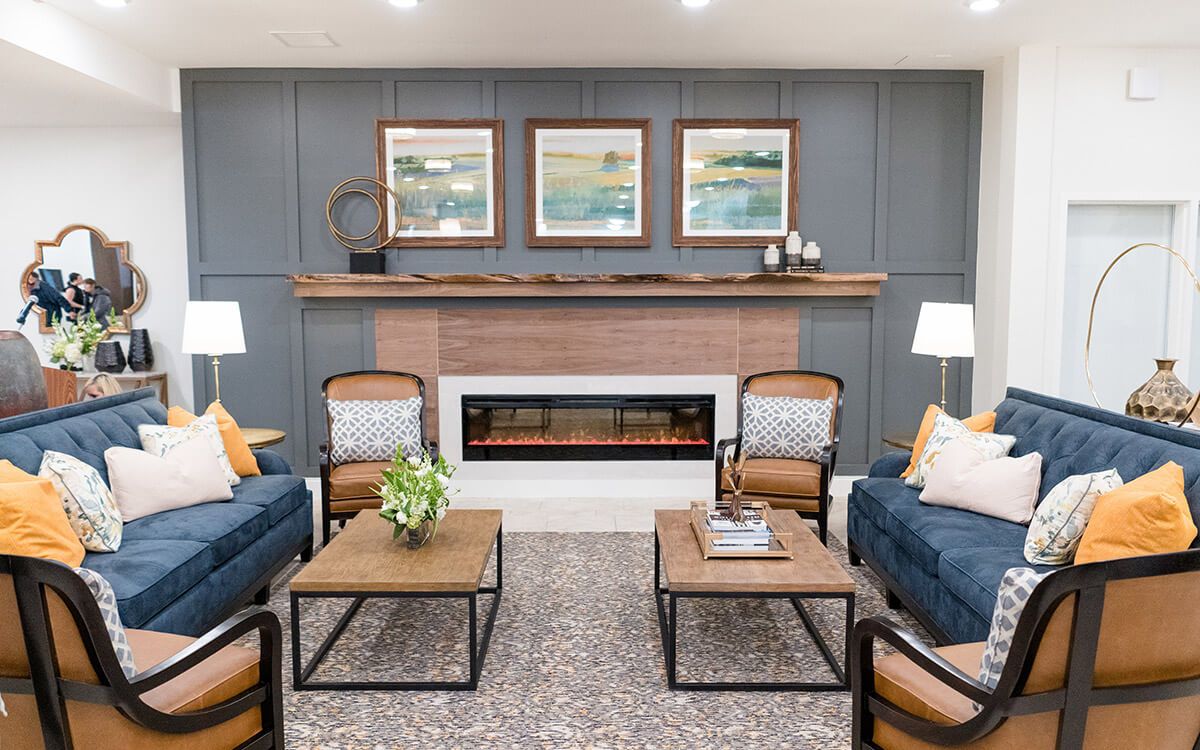 A modern living room with a fireplace, blue sofas, and artwork above the mantel.