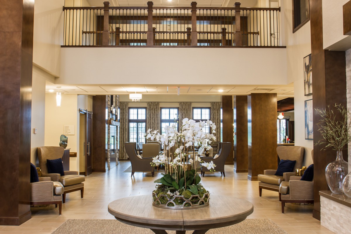 A spacious and elegantly designed lobby with modern furniture and a central floral arrangement.