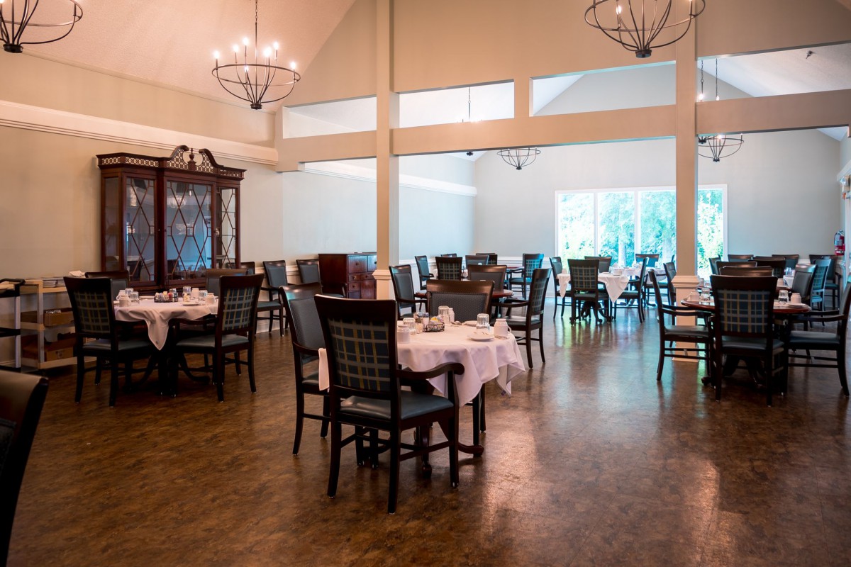 An elegant dining area with empty tables and chandeliers.