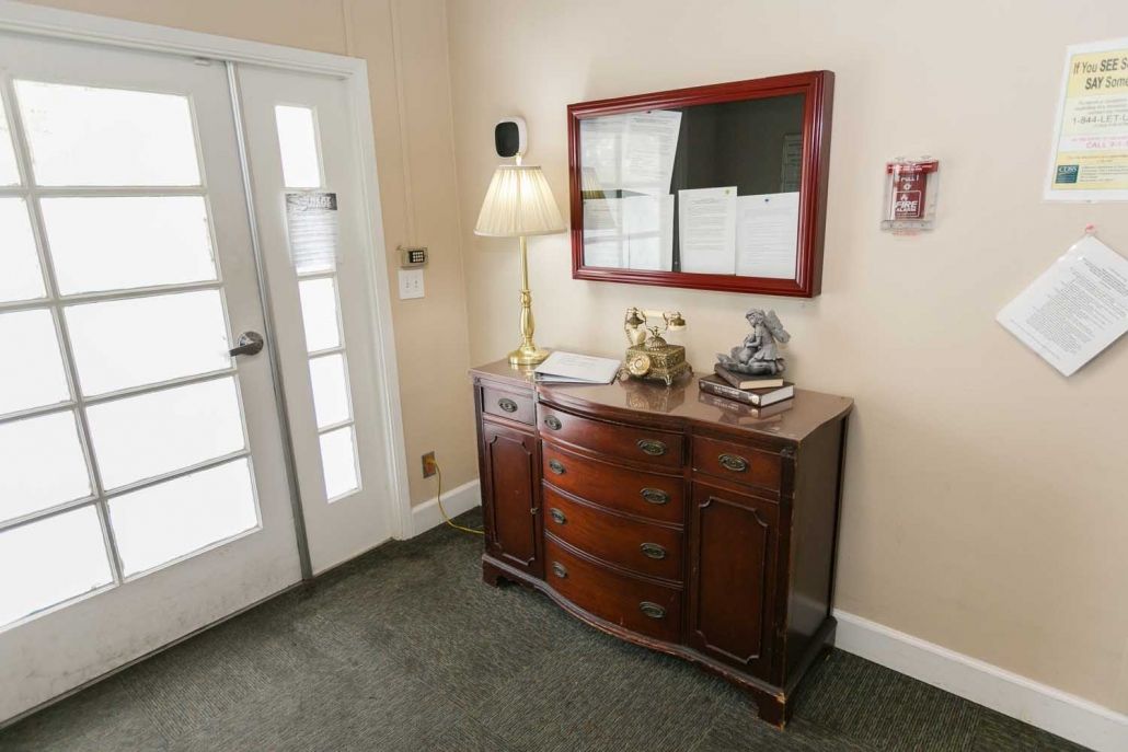 A cozy entrance with a wooden sideboard, decorated with a lamp and mirror.