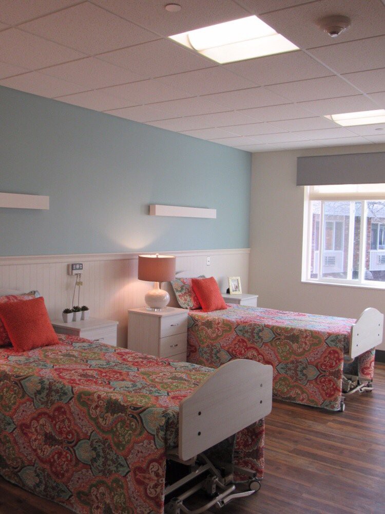 A hospital room with two neatly arranged beds and a window allowing natural light.