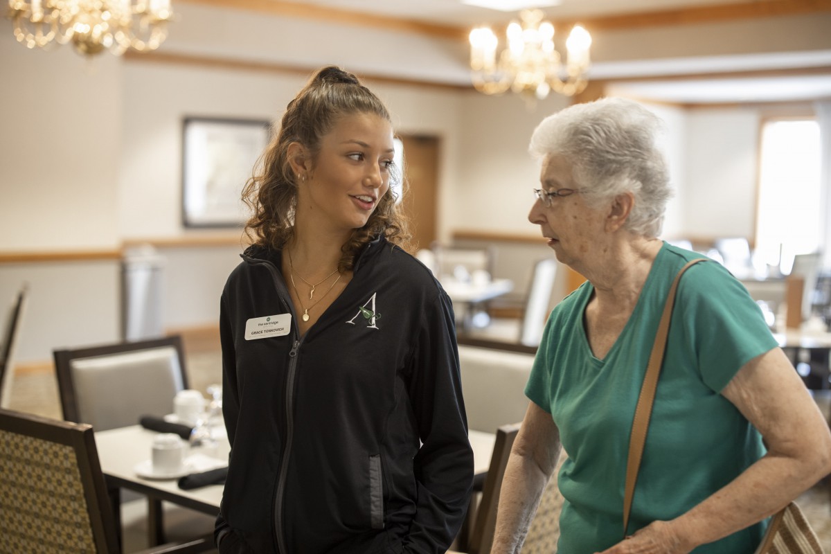 A young woman assisting an elderly woman in a community setting.