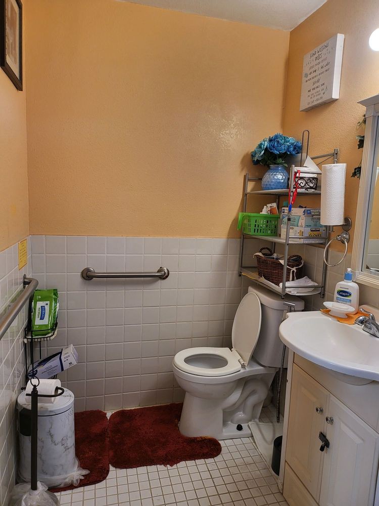 A small bathroom with a toilet, sink, and storage shelves.