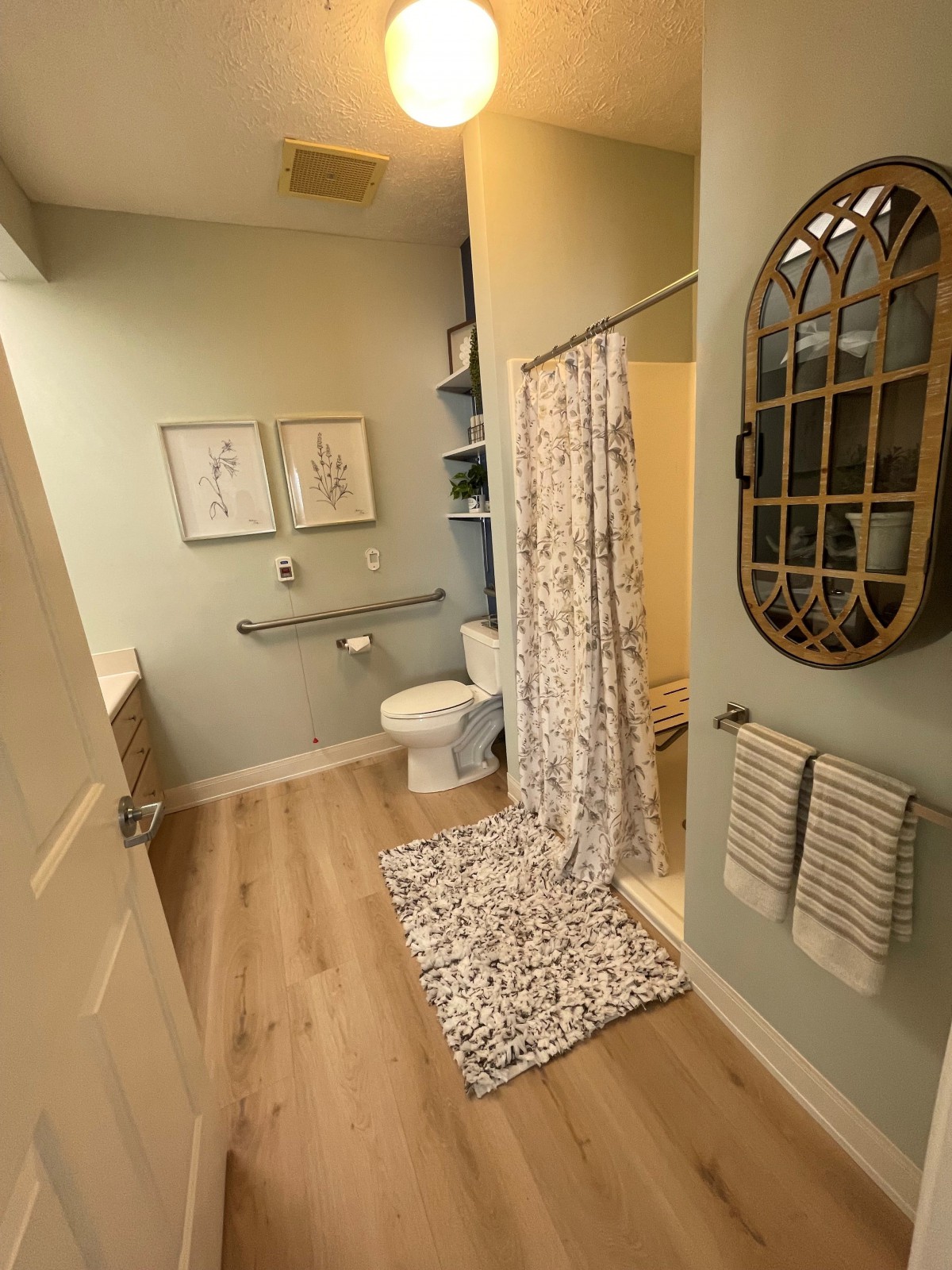A neatly organized bathroom with a shower curtain, wall mirror, and decorative elements.