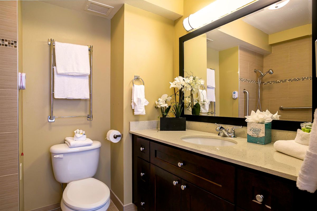 A well-organized bathroom with a sink, toilet, and large mirror.