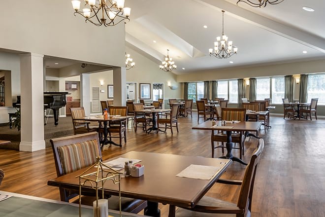 A spacious dining area with wooden floors and elegant chandeliers.