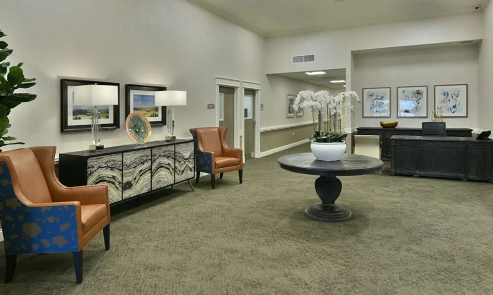 A well-decorated lobby area featuring comfortable chairs, a central table with a potted plant, and elegant lighting.