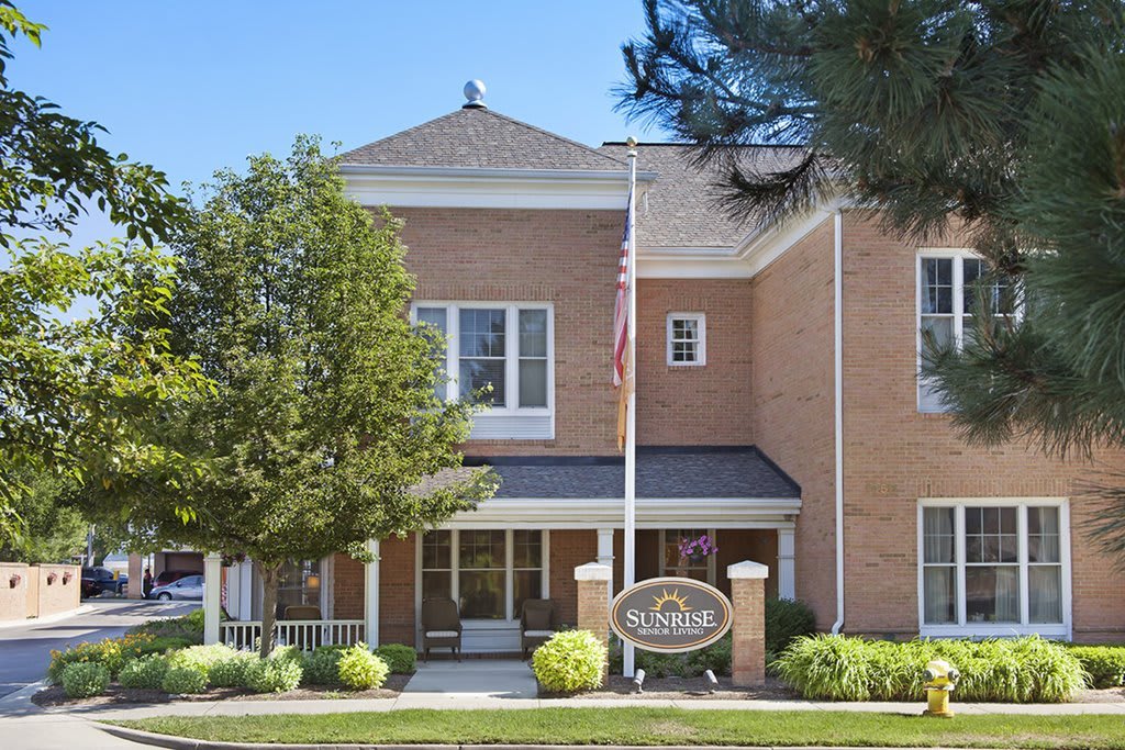 A brick building with a flagpole and landscaped entrance.
